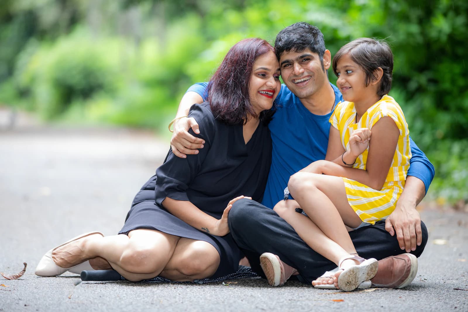 An Indian family sitting close together outdoors, smiling