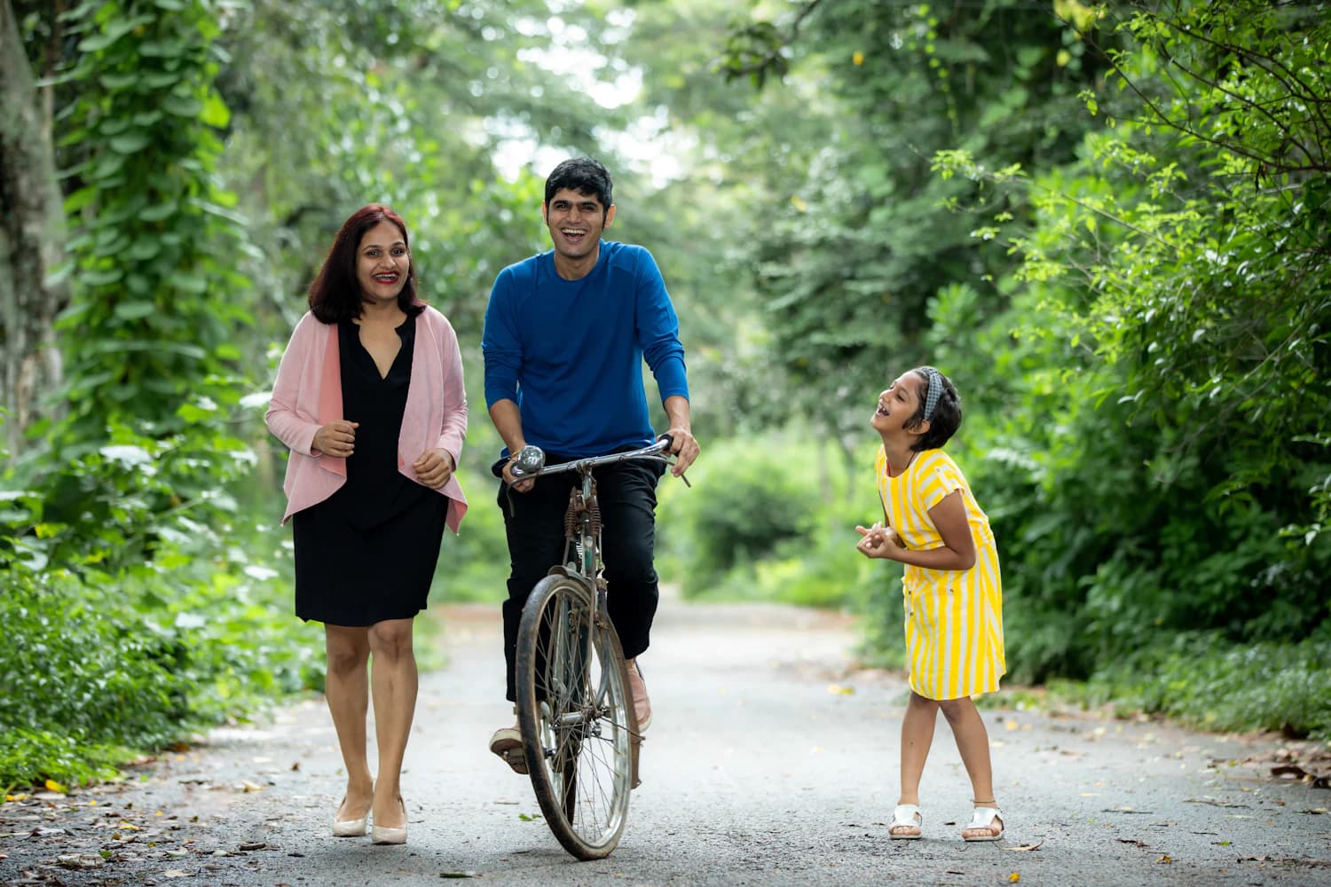 A family walking and cycling together in a green park
