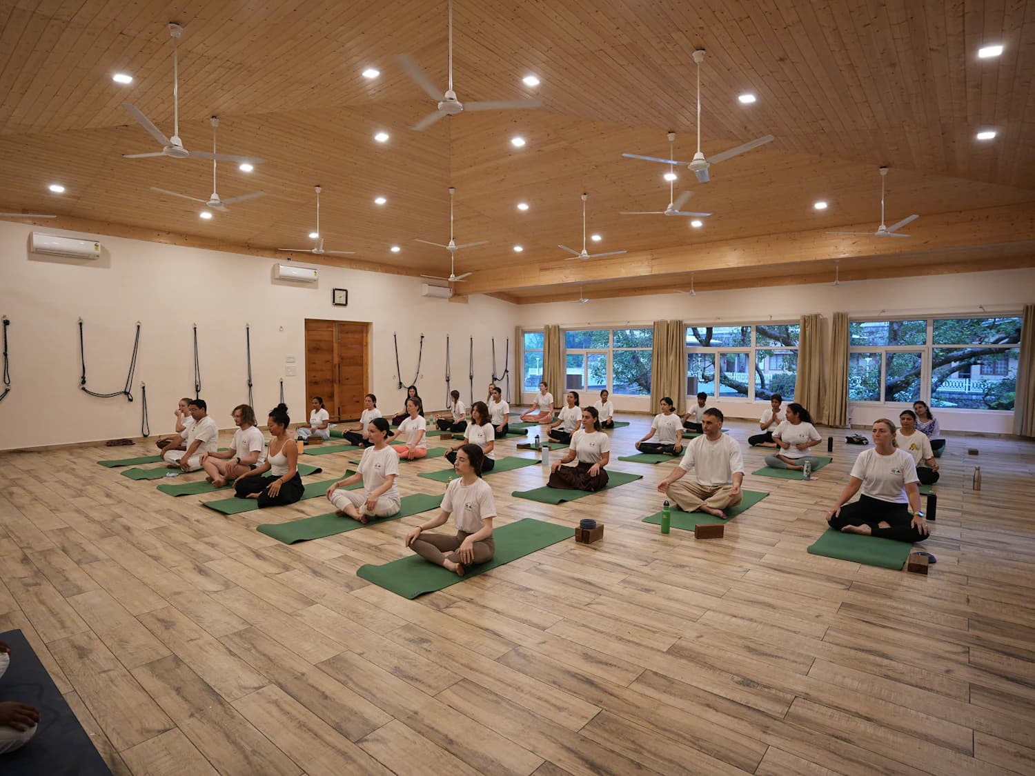 A group session in a bright hall, people seated on mats